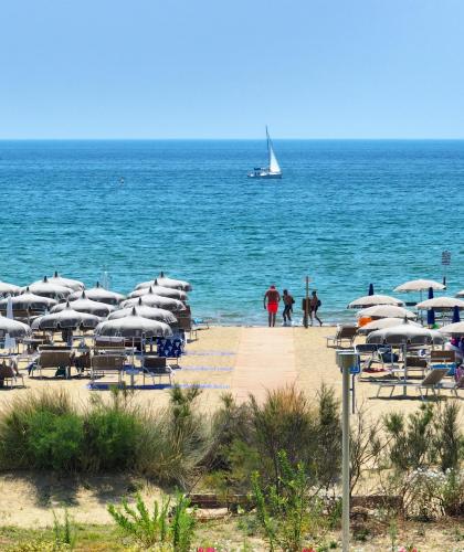 Sandy beach with umbrellas and a sailboat on the sea.