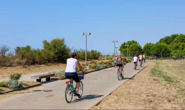 Persone in bicicletta su una pista ciclabile vicino alla spiaggia.