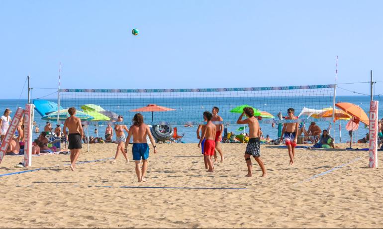 Unge spiller beachvolley på en solrig strand.